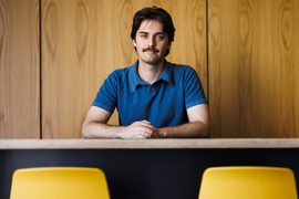 Gage Coon portrait, seated, with two yellow chairs in foreground.