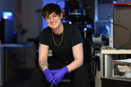 Shannon Knight, wearing nitrile gloves, poses in a chair in her lab