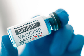 A gloved hand holds bottle of vaccine dosage 