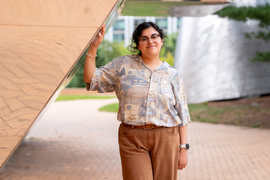 Faith Reyes stands outside Stata, with an arm resting on a diagonal wall.