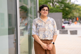 Faith Reyes stands near a window with her reflection