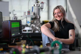 Lanie McKinney, seated, in the lab with oscilloscope and equipment nearby.