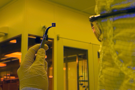 A researcher holding a small chip containing hundreds of devices