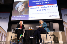 Martha Minow, left, and Sally Kornbluth, right, in conversation on stage with a projected screen behind them with lecture title “Constituting Democracy in the Era of AI.”
