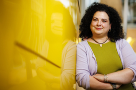 Christina Delimitrou leans against a yellow wall outside of Stata Center.