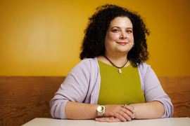 Christina Delimitrou portrait, seated, with yellow background