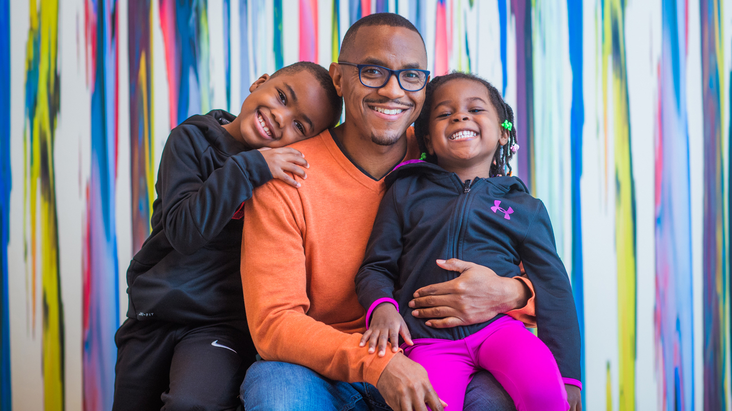 ElDante Winston with his two children in front of colorful wall