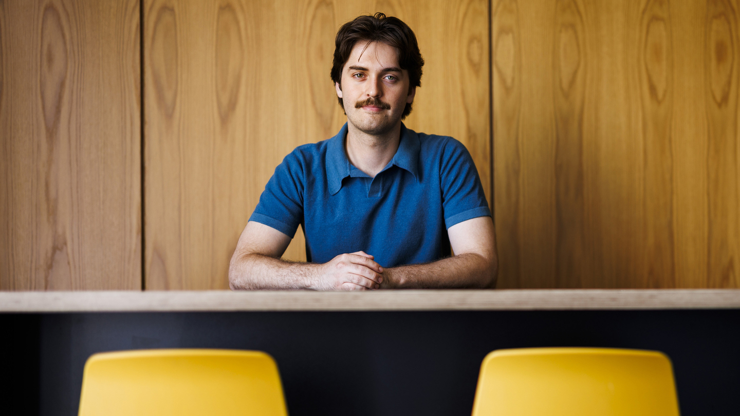 Gage Coon portrait, seated, with two yellow chairs in foreground.