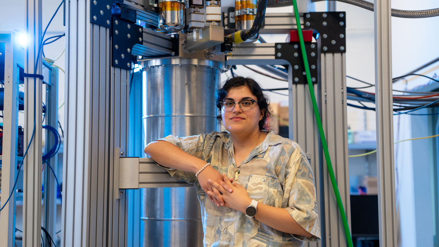 Faith Reyes stands in front of a large device in the lab.