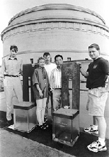 Prototypes of the 168 chairs that will form a memorial to commemorate the victims of the Oklahoma City bombing were weather-tested on the roof of an MIT building over the summer. Left to right: design firm members Sven Berg (far left), Torrey and Hans Butzer, and MIT Professor Yet-Ming Chiang and graduate student Ben Hellweg, who did the testing.