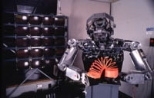 This picture of Cog, a humanoid robot created by a team of researchers at the AI Lab led by Professor Rodney Brooks, was taken in March 1998. Cog is playing with a Slinky toy; the bank of computers to his right is linked to his vision. See related story on Humanoid2000 conference.