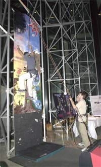 One team in 2.009 built a remote-controlled rope-belaying system for use in gyms and health clubs. Two seniors in mechanical engineering demonstrate the device; on the climbing wall is Luis M. Otero and behind him on the ground, strapped as a safety backup during the demonstration, is Oren Bernstein.