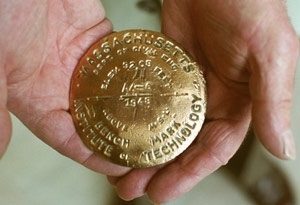 A closeup of the brass benchmark (in alumnus Philip Simmons' hands)        that he placed on a bridge road in Maine in 1948.