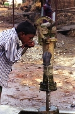 A young boy drinks polluted water from the village pump. This tube well's water has microbial contamination.