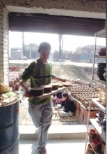 MIT student Jason Low carries a tray of casings for filters through the doorway of Hari Gobindh's pottery in a village near Kathmandu.