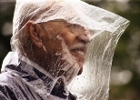 Armand Villar employs some plastic weather protection as he watches his grandson Carlos Garcia graduate .