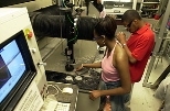 RISE students Stacie Meadows of University of Michigan and partner Anthony Pullen of the Southern University of Louisiana watch as their stone tile is cut out under water. They designed their tile, including the message being inscribed as part of the Temple of Technology, on the computer at left.