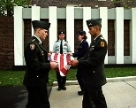 Army Master Sgt. Kraig Haas, a military science instructor (background), is flanked by Army ROTC cadet Benjamin Smith (left), a sophomore in mechanical engineering; Air Force cadet Georgene Hilb, a junior in aeronautics and astronautics; and Army cadet Aneal Krishnan, a senior in electrical engineering and computer science, as they fold the flag from the veiled Reflecting Wall.