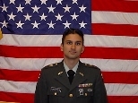 Wearing dress uniform, Commander Krishnan poses for a formal portrait in front of the American flag.