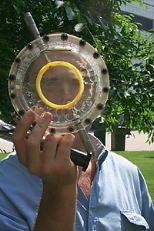 Graduate student Saul Griffith looks through the lens molder of the portable device he invented to make low-cost prescription eyeglasses for people in the developing world. He won the Collegiate Inventors Competition and was inducted into the Inventors Hall of Fame.