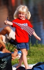 Lindsey Deluga of Lake Zurich, Ill waves a flag on the Esplanade while waiting for the start of the fireworks.