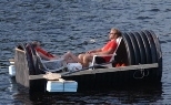 MIT graduate students John M. McBean and Cecile Le Cocq relax on the Charles River before the start of the fireworks in a homemade boat made from an old sewer pipe.