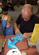 Boston University Professor Richard Brower, a visiting scientist at the Center for Theoretical Physics, shows his three-year-old son, Robert, how to make paper airplanes.