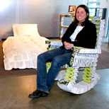 MIT employee Stephanie Hartman relaxes in a rocking chair she made out of campus phone directories, part of a book-based bedroom suite on view in Rotch Library.