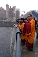 Buddhist monk Tenzin Yignyen (with vase) pours the sand from the Chenrezig Mandala into the Charles River after Tenzin L.S. Priyadarshi, MIT's Buddhist chaplain (front), blew a conch shell.