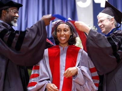 Ebonya Washington, center, is hooded by MIT Chancellor Phillip Clay, left, and Professor Bengt  Holmstrom, department head in the School of Humanities, Arts and Social Sciences. Washington earned her Ph.D. in economics.