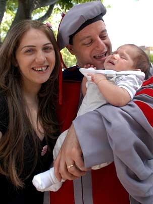 Newly hooded with his economics Ph.D from MIT. is Samer M. Haj-Yehia, center, holding his newborn son Saji, as wife Adan smiles proudly.