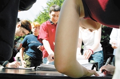 Senior Ben Wagner (center) helps graduate student Sian Kleindienst (foreground) register to vote during a Rock the Vote event on Kresge Oval.
