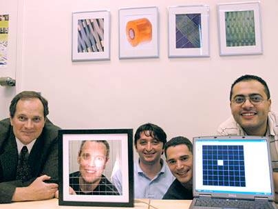 Researchers display the new light sensitive fabric  they have created, fibers of which are in front of Yoel Fink's face in frame. From left to right are physics professor John Joannopoulos, material science professor Yoel Fink, post-doc Mehmet Bayindir, graduate student Fabien Sorin and post-doc Ayman Abouraddy.