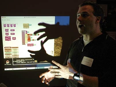 At the Educational Technology Fair, Professor Eric Klopfer of urban studies and planning gestures in front of his computer screen as he describes how he integrates handheld devices into his courses.