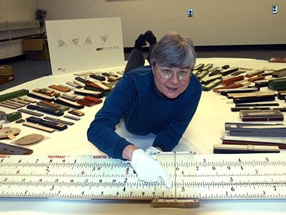 Deborah Douglas, curator of science and technology for the MIT Museum, sprawls among some of the 600 historic slide rules that were recently donated to the museum.