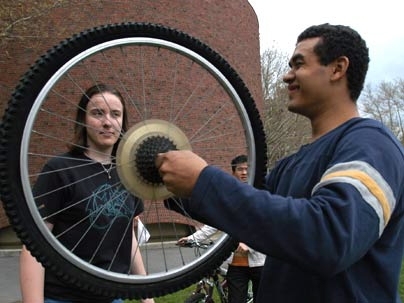 Sophomores Kay Aull, left, and Jose Solten confer about Aull's bent wheel during an MIT Earth Day bike repair workshop on Kresge Oval.
