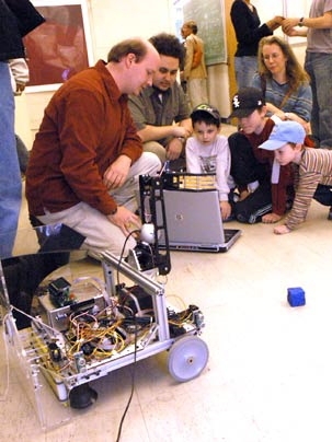 David Nelson, a graduate student in electrical engineering and computer science (EECS), explains how his group's machine works during an inauguration week presentation May 5 by the class Robotics Science and Systems I. Next to him is EECS senior Javier Velez, Christopher Tighe, older brother Greg, former employee Kathryn Gandek-Tighe and middle brother Eric Tighe.