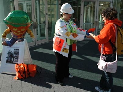 Community Giving volunteer Melissa Kavlakli, in hard hat, offers Cristina Ximenes some candy and a reminder about MIT's annual Community Giving Campaign outside the Stata Center 77 Mass. Ave. on Monday, Oct. 31. "Helping people can be a real screeeeam!" the card said.