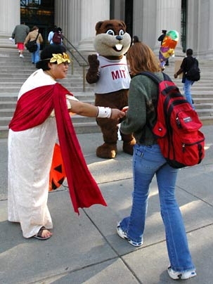 Y-Chie Primo, left, offers a passerby candy and information about MIT's annual Community Giving Campaign outside 77 Mass. Ave on Halloween.  Tim, the MIT mascot, waves in the background.
