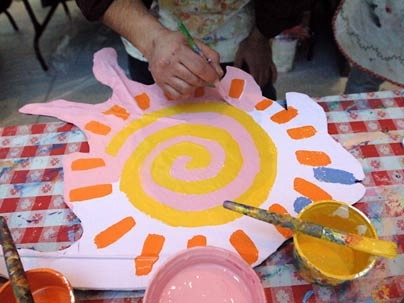 An artist works on one of the many colorful fish that are now hanging in the Stata Center as part of an installation called 'S.O.S.-Fish.'