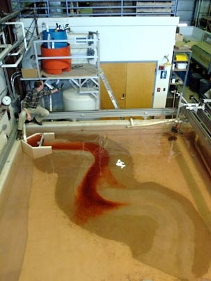 At MIT's Morphodynamics Laboratory, research scientist James Buttles adjusts the inflow valve of a sediment-laden, gravity-driven current flowing in an experimental channel. Observing how the sediment is deposited in and around the channel is providing new insights into the structure of oil-rich sediment-filled channels found deep under the sea floor.