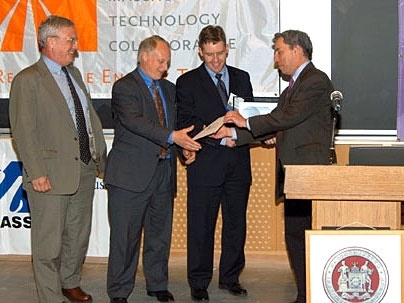 Warren Leon presents the top prize in the 2006 Ignite Clean Energy Business Presentation Competition to representatives of Stellaris, from left, Jim Paull, president and co-founder; Tom Ward, vice president; and Lee Johnson, chief operating officer and co-founder.