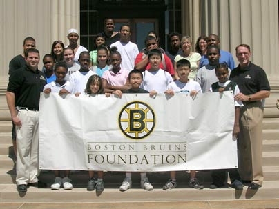 Jay Southwood, left, and Paul Stewart of the Boston Bruins Foundation hold up their foundation's banner on the steps in Killian Court on July 24 with the help of some students from the Science, Technology, Engineering and Math program. The foundation has given the program $25,000.