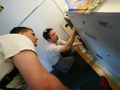 MIT graduate student Bryan Urban, left, and alumnus Phil LaFond, who works for Climate Energy, look over one of the company's residential generators, which produces both heat and electricity.