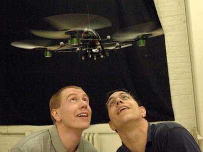 MIT graduate students Brett Bethke, left, and Mario Valenti watch an unmanned aerial vehicle, one in a fleet of four they helped develop to execute surveillance and tracking tasks.
