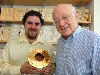Research scientists Justin Kasper and Alan Lazarus display a Faraday Cup, a device used to measure the current in a beam of charged particles.