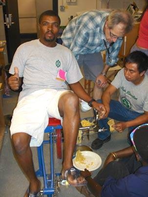 From left, Clarel Jerome of Haiti, a participant in MIT's International Development Design Summit; Gwyndaf Jones, a bicycle expert from the U.S., and Carlos MarroquÃn, a participant and Native American from Guatemala, are using a pedal-powered device to mill corn for the participants to cook. <a onclick="MM_openBrWindow('summit-4-enlarged.html','','width=509, height=583')">
<span onmouseover="...