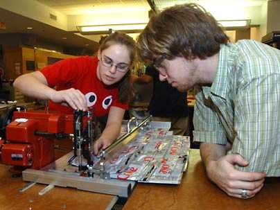 Nicolina Akraboff, left, works on an MIT product engineering course project while Roderick La Foy looks on. The two mechanical engineering seniors were part of a team that sewed discarded, flattened plastic bottles together to create insulation for thin walls in Pakistani homes.