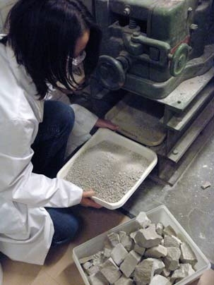 Sophomore Stephanie Brown feeds limestone chunks into a machine to pulverize it into a form the class can later turn into concrete.