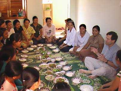 Alan Lightman, at right, shares a meal with Cambodian students.  The Harpswell Foundation, which he and his wife founded, built a dormitory for the women so they could attend college in Phnom Penh.